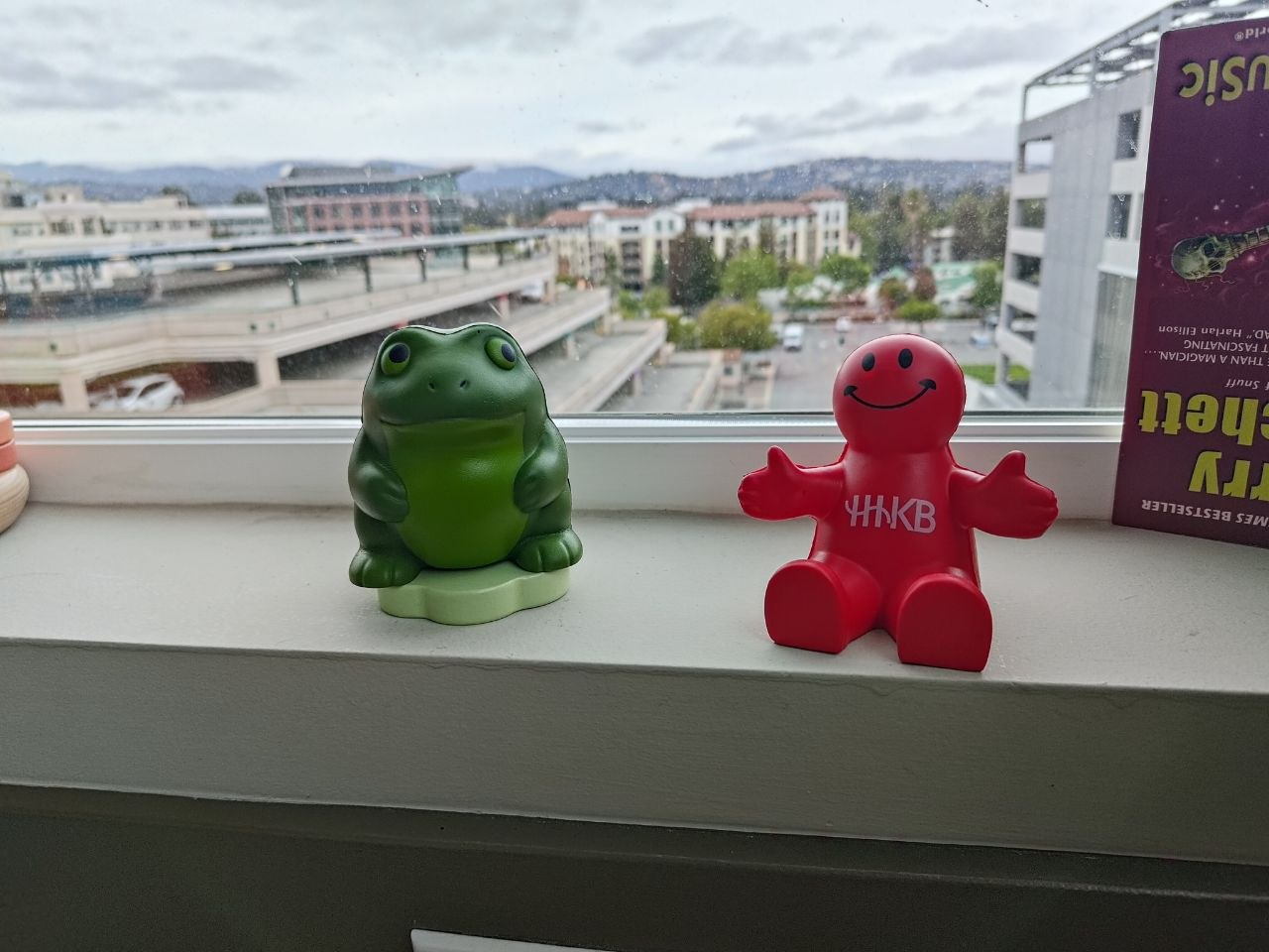 Original photograph of a green frog and red HHKB toy on a windowsill.